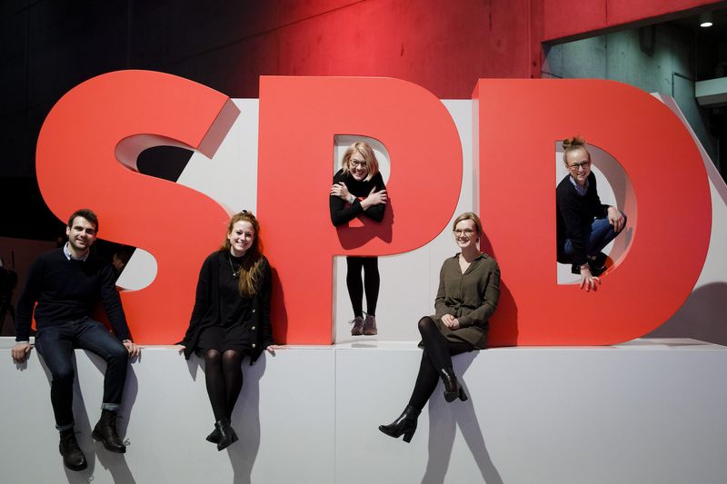 Foto: Junge Menschen sitzen rundum ein großes SPD-Logo